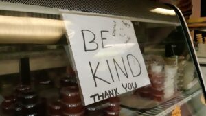 A "Be Kind" sign in the display window at the Kool Deelites ice cream store on Harbison Ave west in Winnipeg, Manitoba.